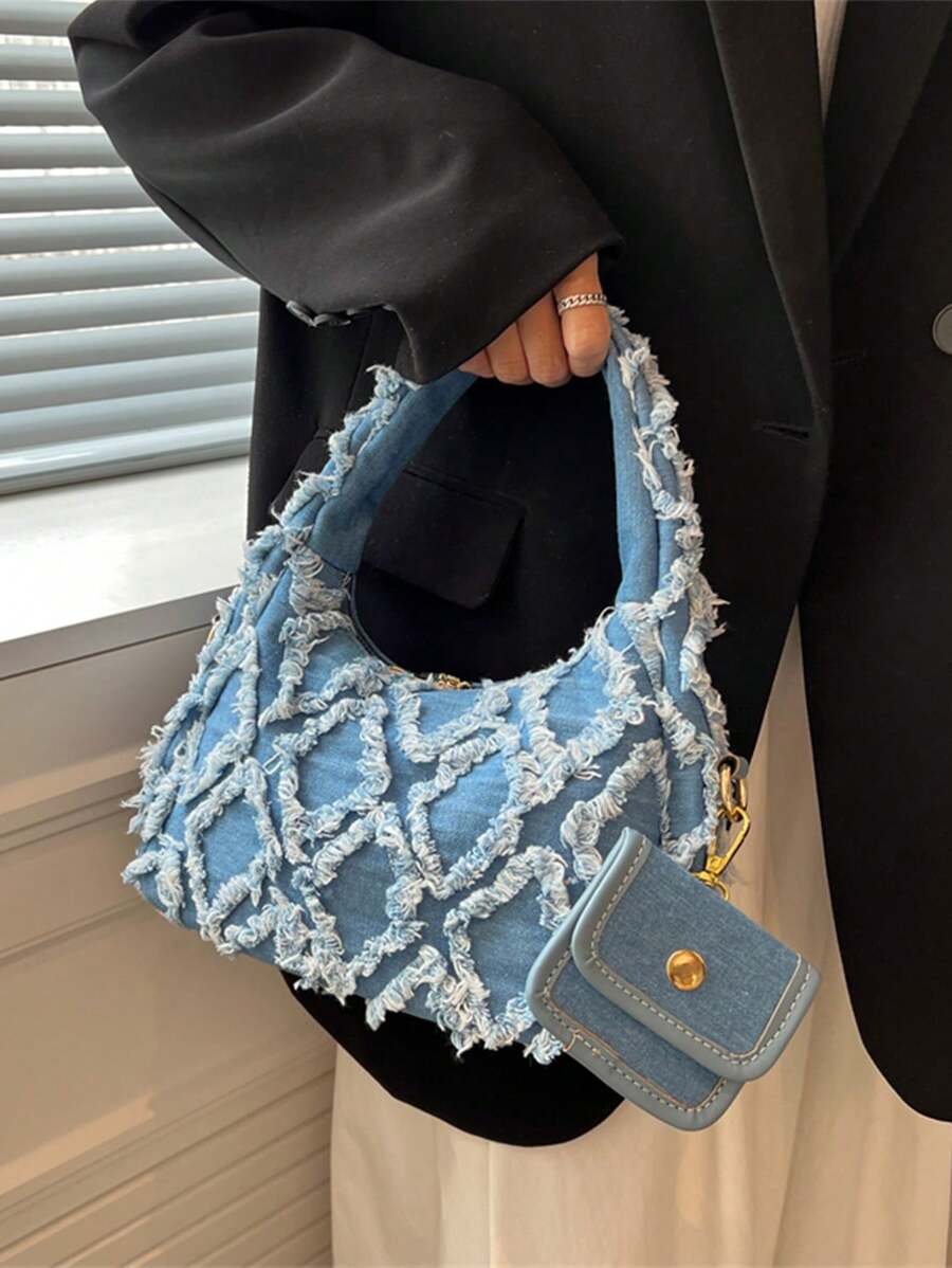 sac bleu brodee effilochee en jeans tenu par la main