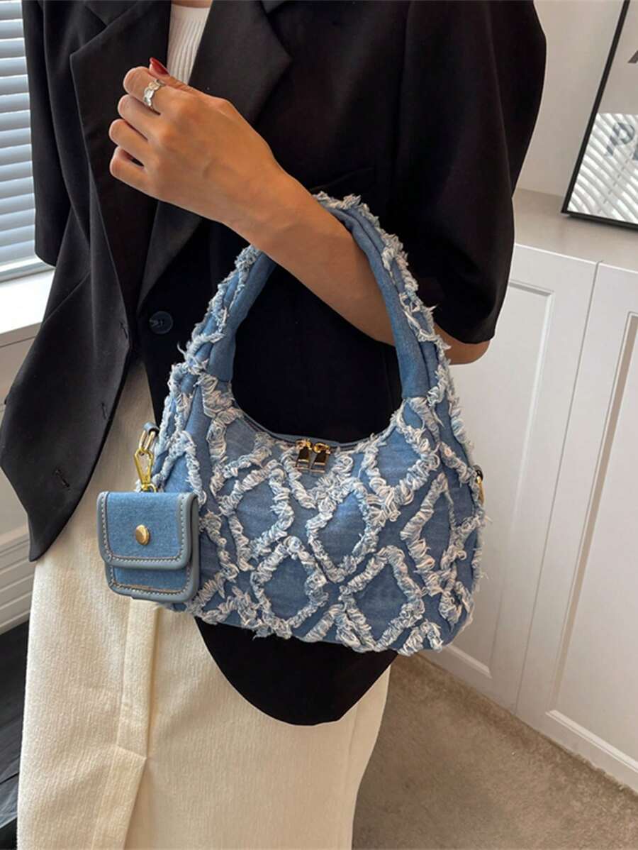 sac bleu brodee effilochee en jeans tenu par la main gauche femme elegante