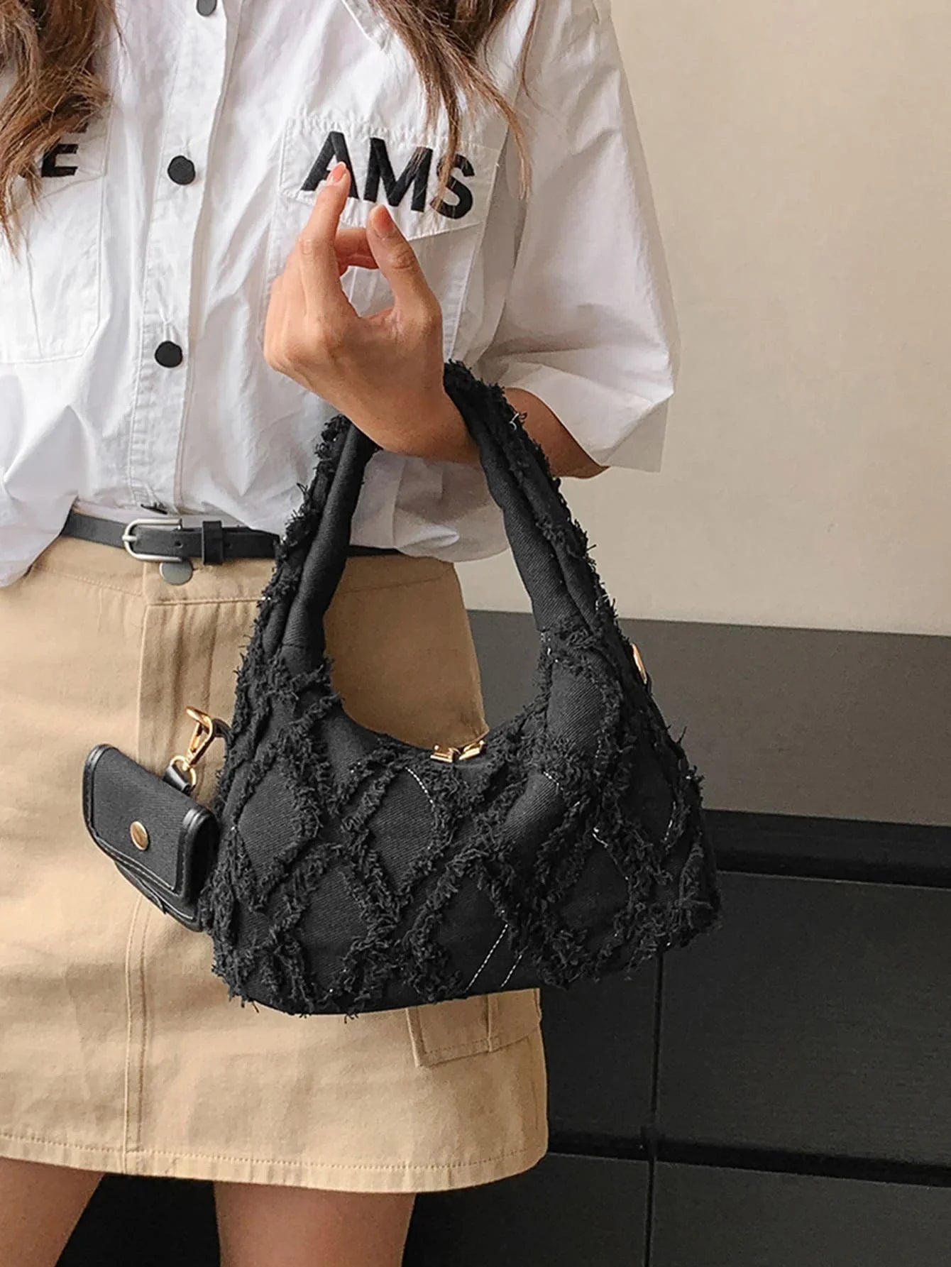 sac noir style effilochee brodee femme portant main gauche