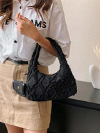 sac noir style effilochee brodee femme portant sur l'epaule droite et main droite 